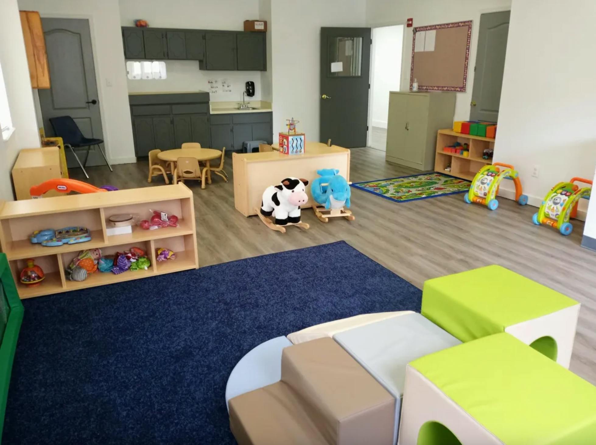 Playroom with soft play equipment, toys, and small tables