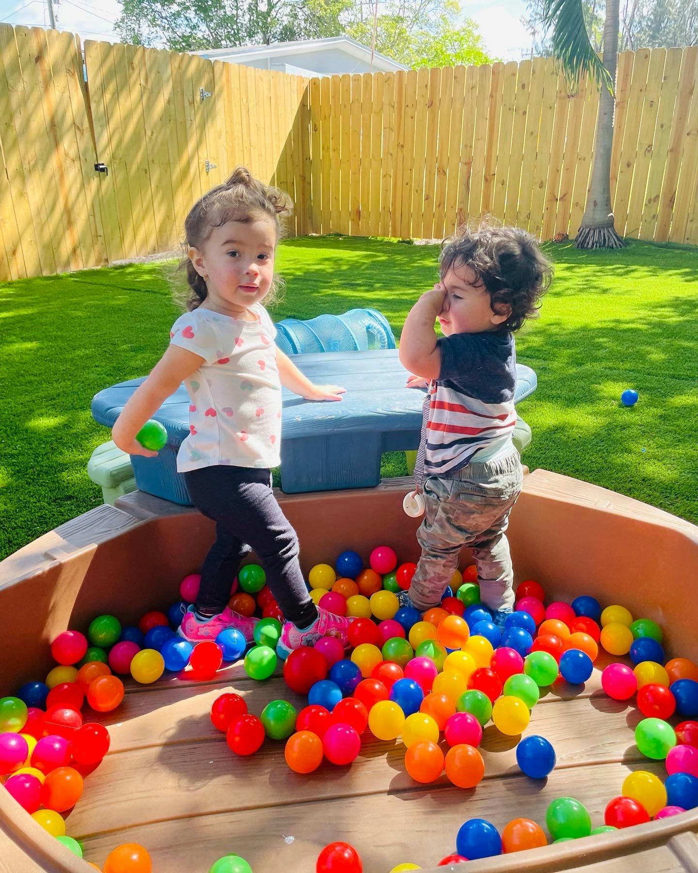 Two children playing in a ball pit outdoors