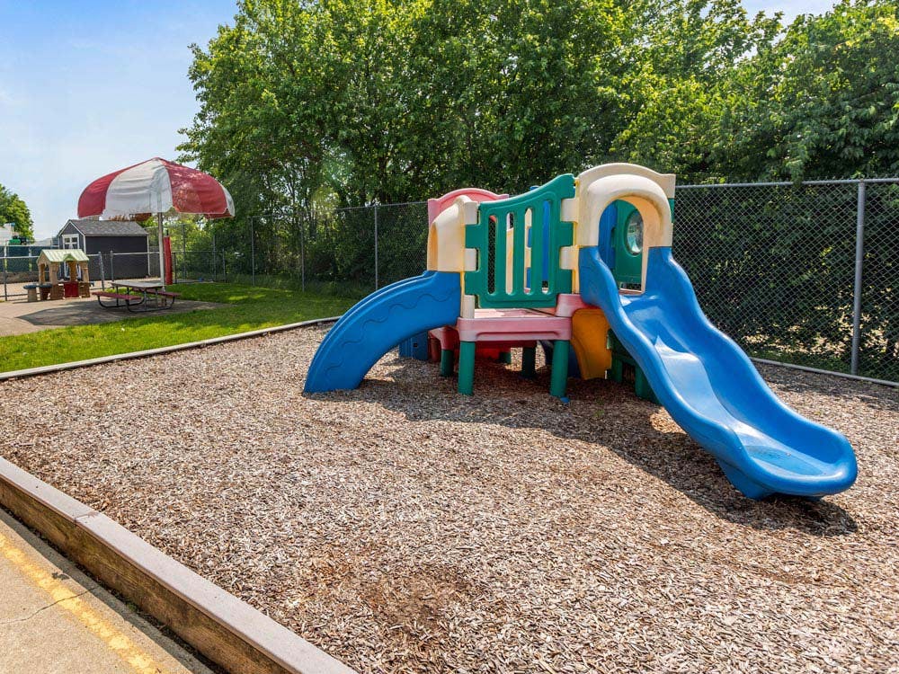 Colorful playground structure with two blue slides and wood chips on the ground