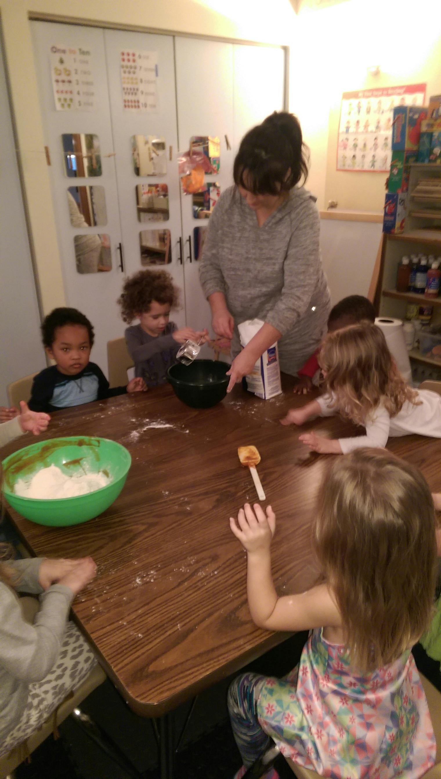 Adult and children mixing ingredients in bowls at a table
