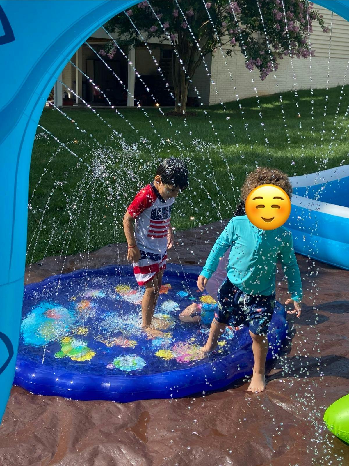Two children playing in a splash pad with water spraying over them