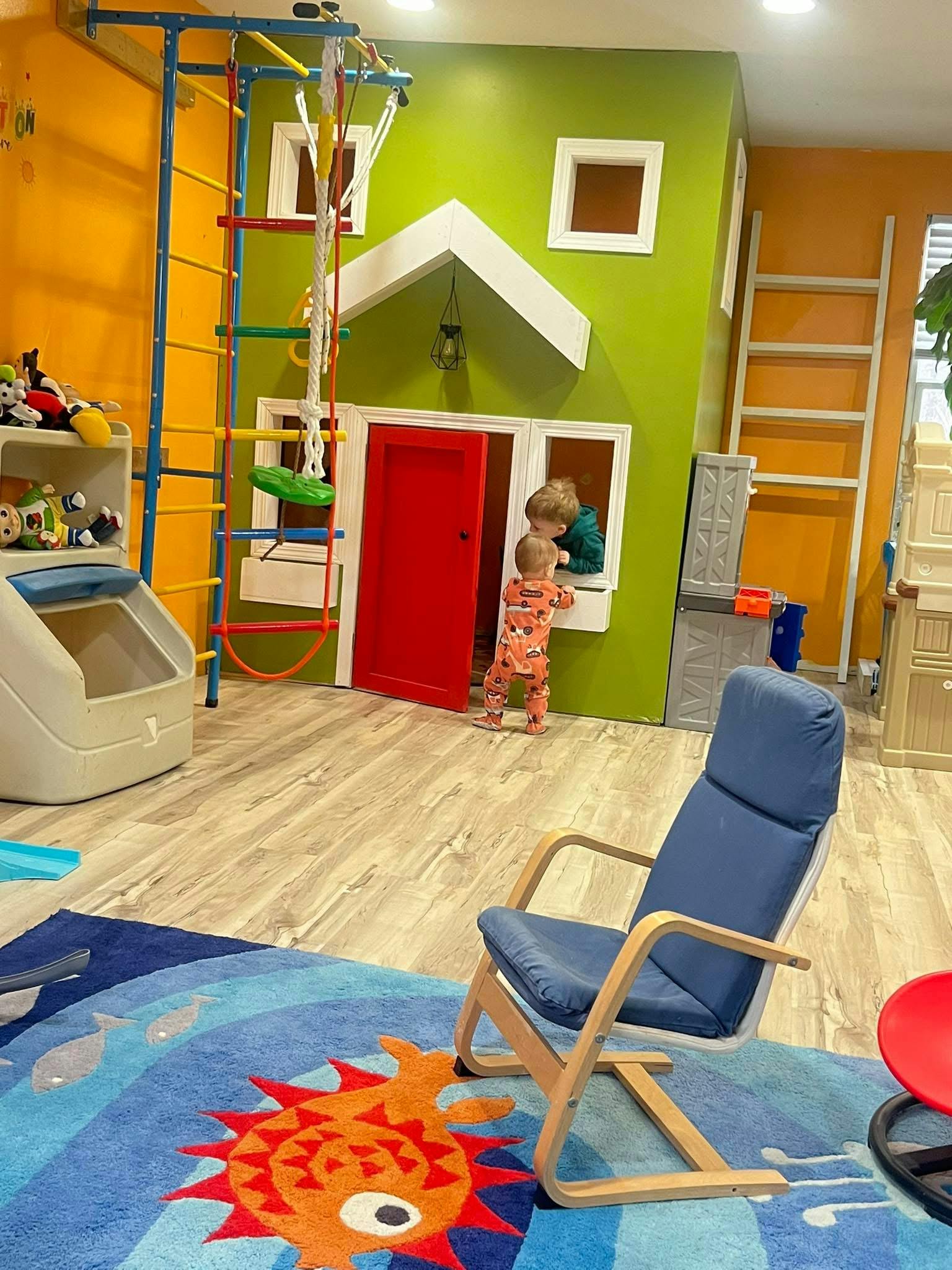 Two children playing at a toy house in a playroom