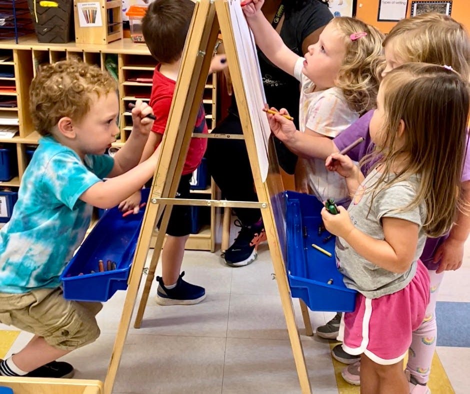 Children drawing on easels in a classroom