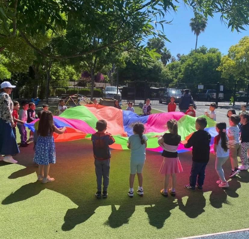 Group of children holding a colorful parachute on a playground