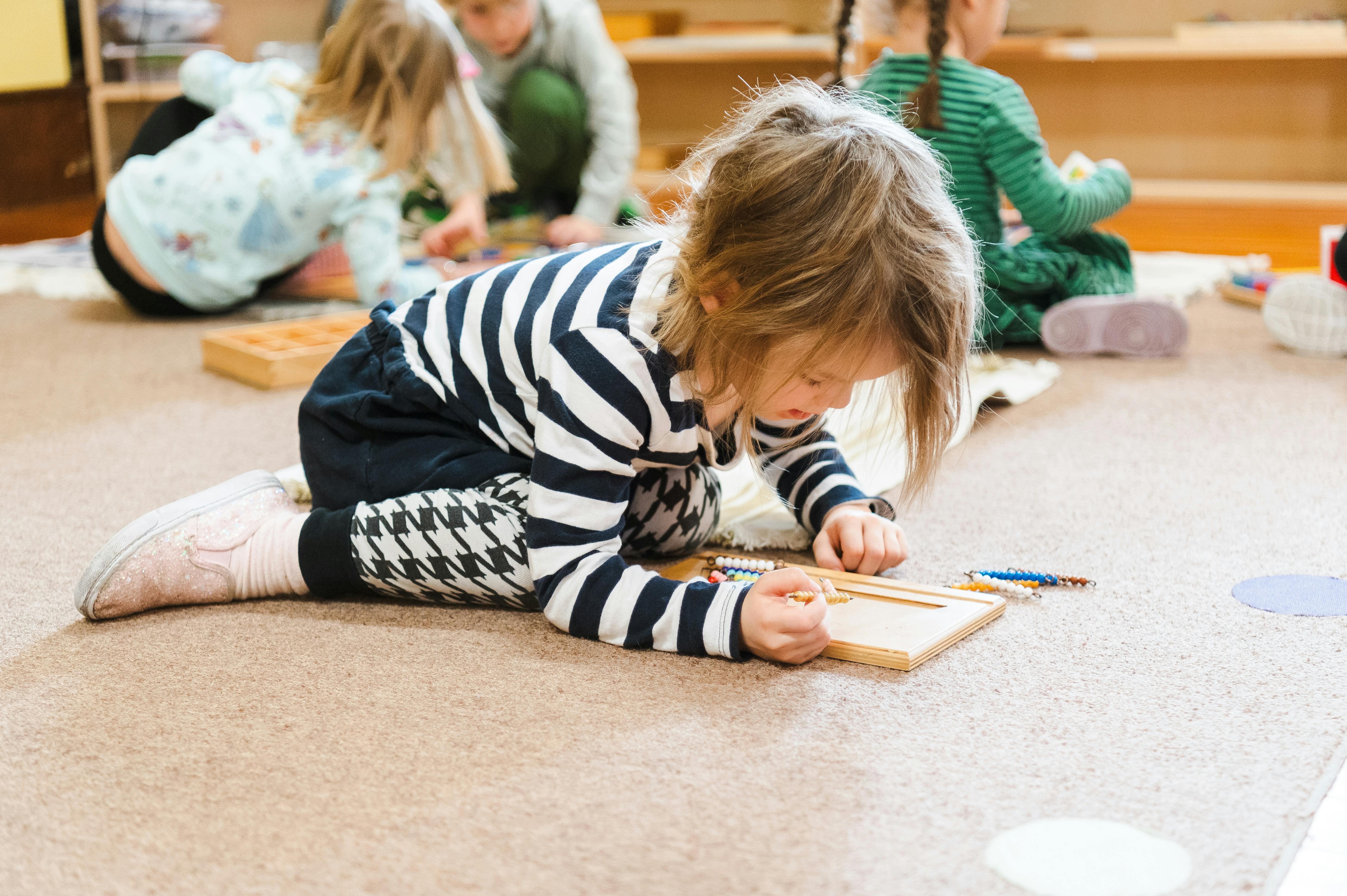 Child on floor playing with wooden blocks inlays in a classroom