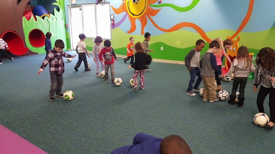 Children playing with soccer balls indoors