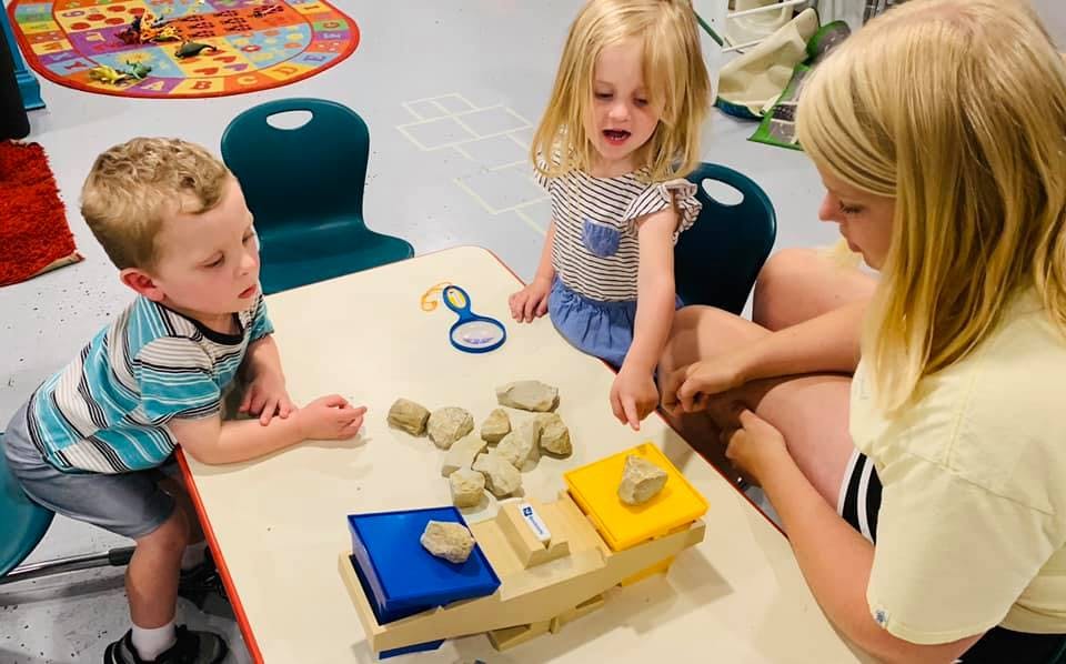 Three children playing with clay at a table