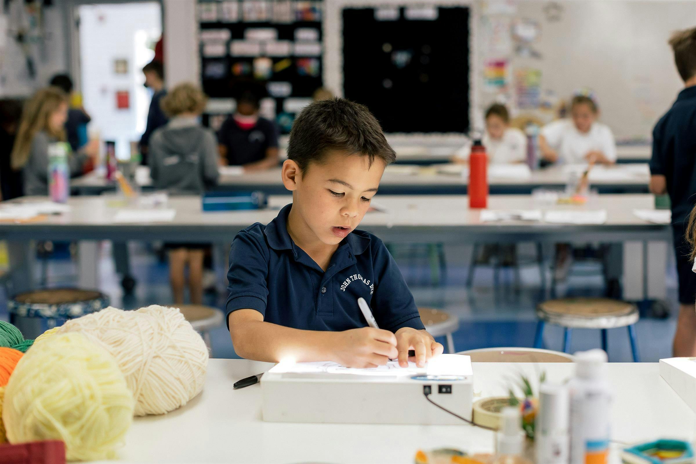 Child drawing on a light box in a classroom