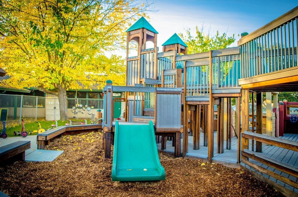 Playground with a green slide and wooden structures
