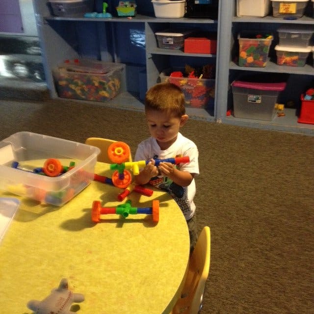 Child playing with colorful building toys at a yellow table