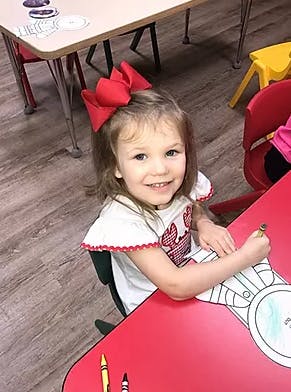 Child coloring at a red table