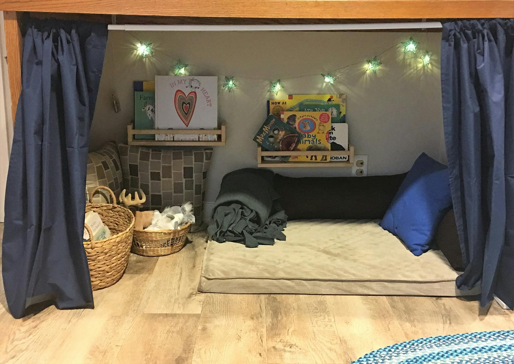 Cozy reading nook with mattress, pillows, blankets, and string lights