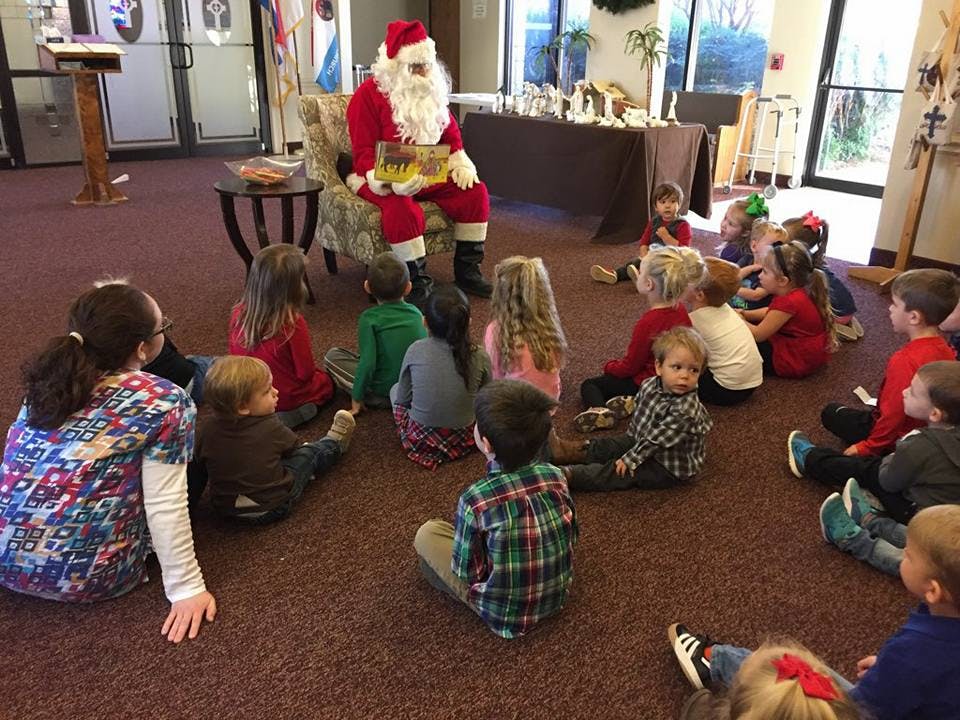 Person dressed as Santa Claus reading to a group of children