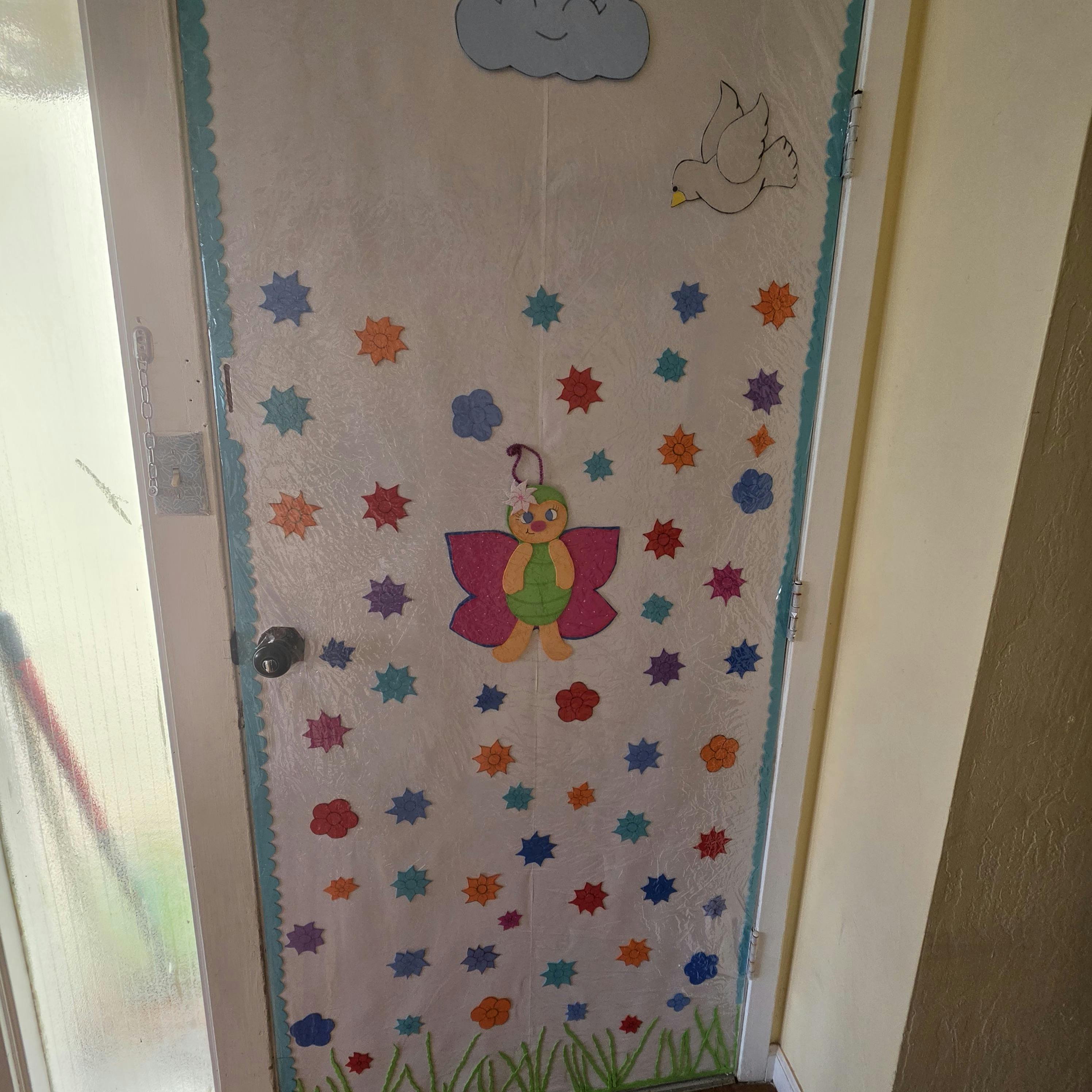 Door decorated with a butterfly, flowers, cloud, and bird cutouts