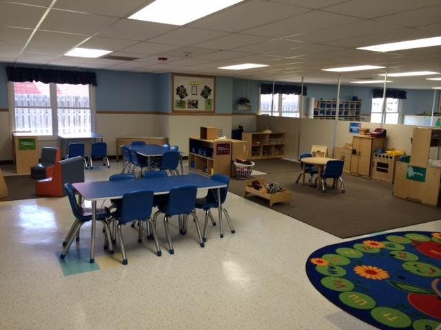 Empty children's classroom with small blue tables and chairs