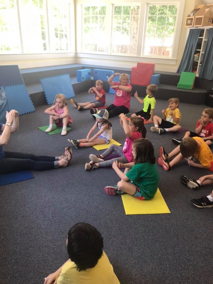 Adult and children sitting on the floor in a classroom
