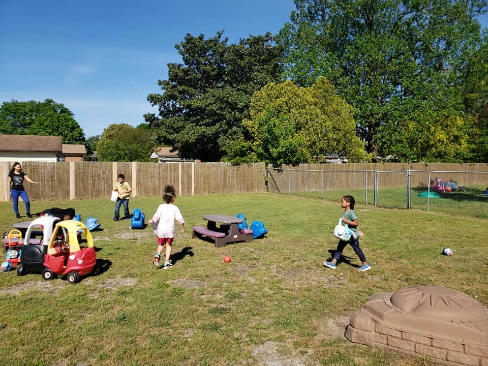 People and children playing in a grassy backyard
