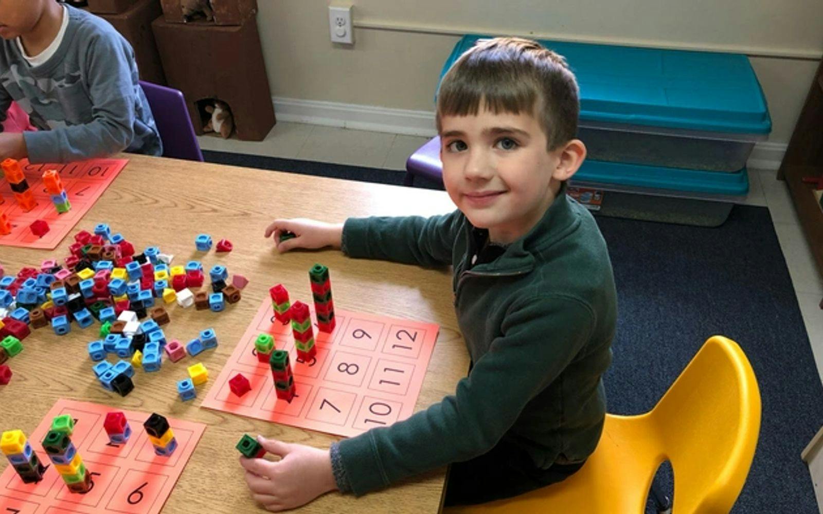Child at a table with building blocks and number cards