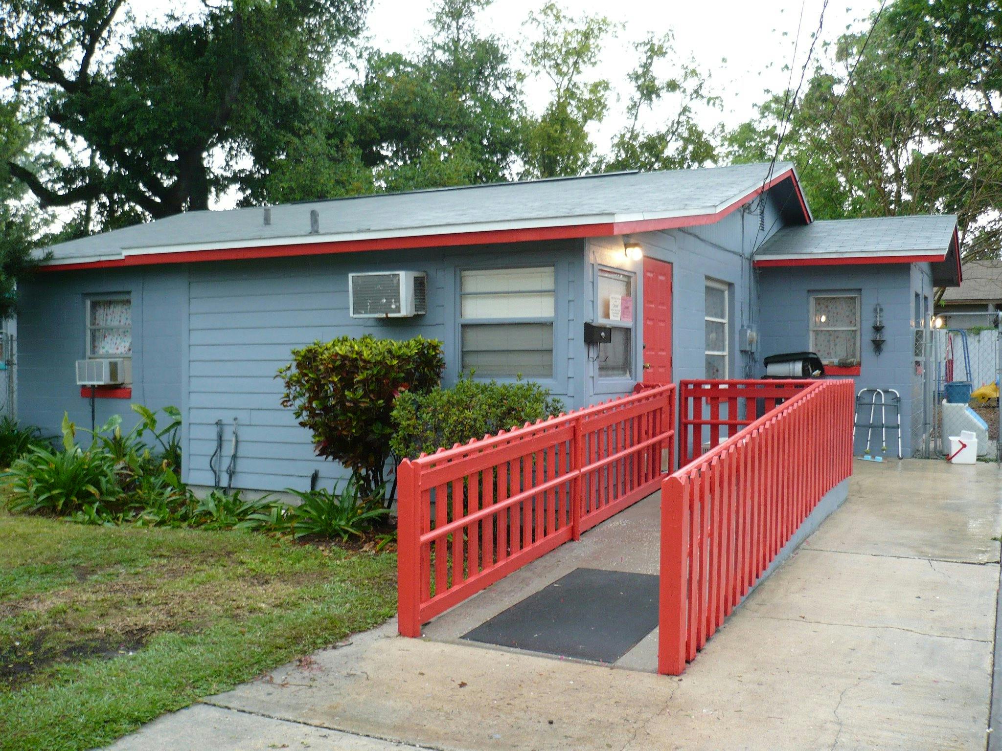 Small house with a red accessibility ramp leading to the front door