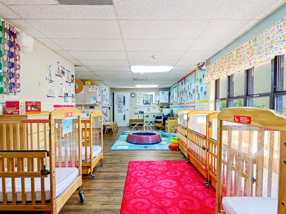 Baby room with several cribs and colorful rugs