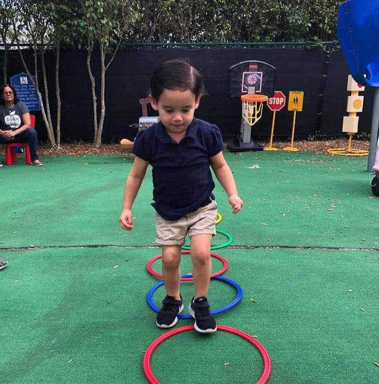 Child stepping through colorful hoops on a green surface