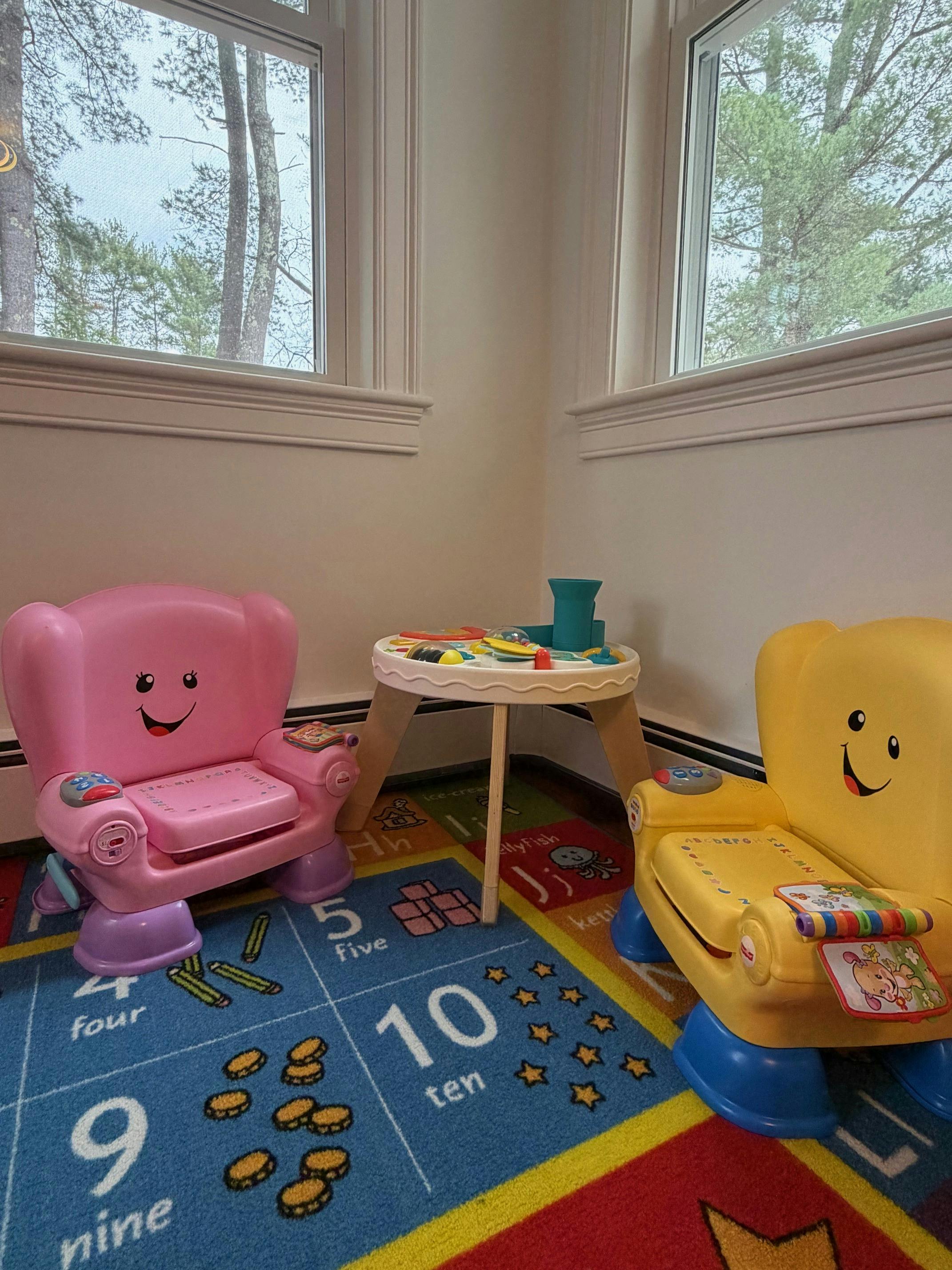 Pink and yellow child chairs with a small table on a colorful rug