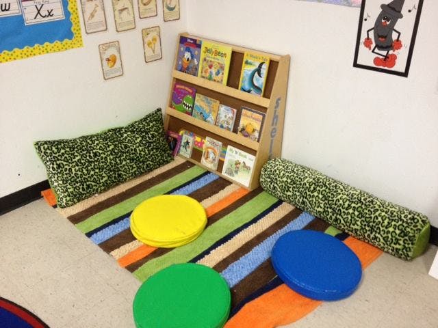 Reading nook with a bookshelf, striped rug, pillows, and floor cushions