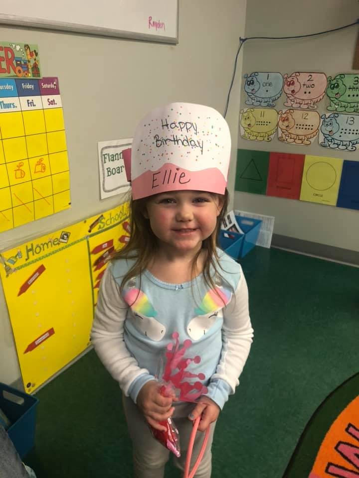 Child wearing a "Happy Birthday Ellie" hat