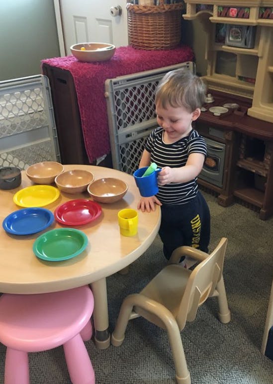 Child playing with colorful plates and bowls at a small table