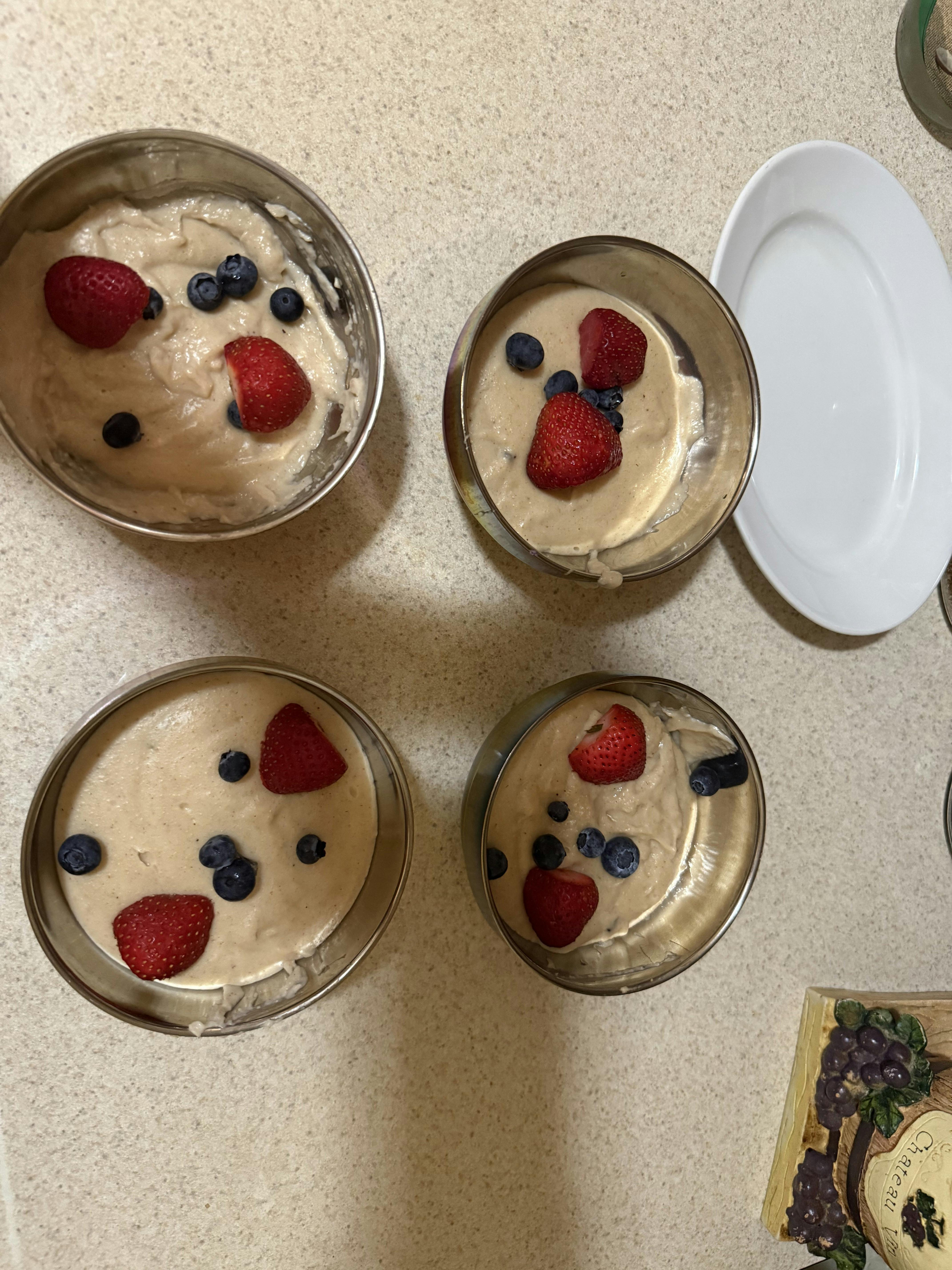 Four bowls containing porridge topped with strawberries and blueberries