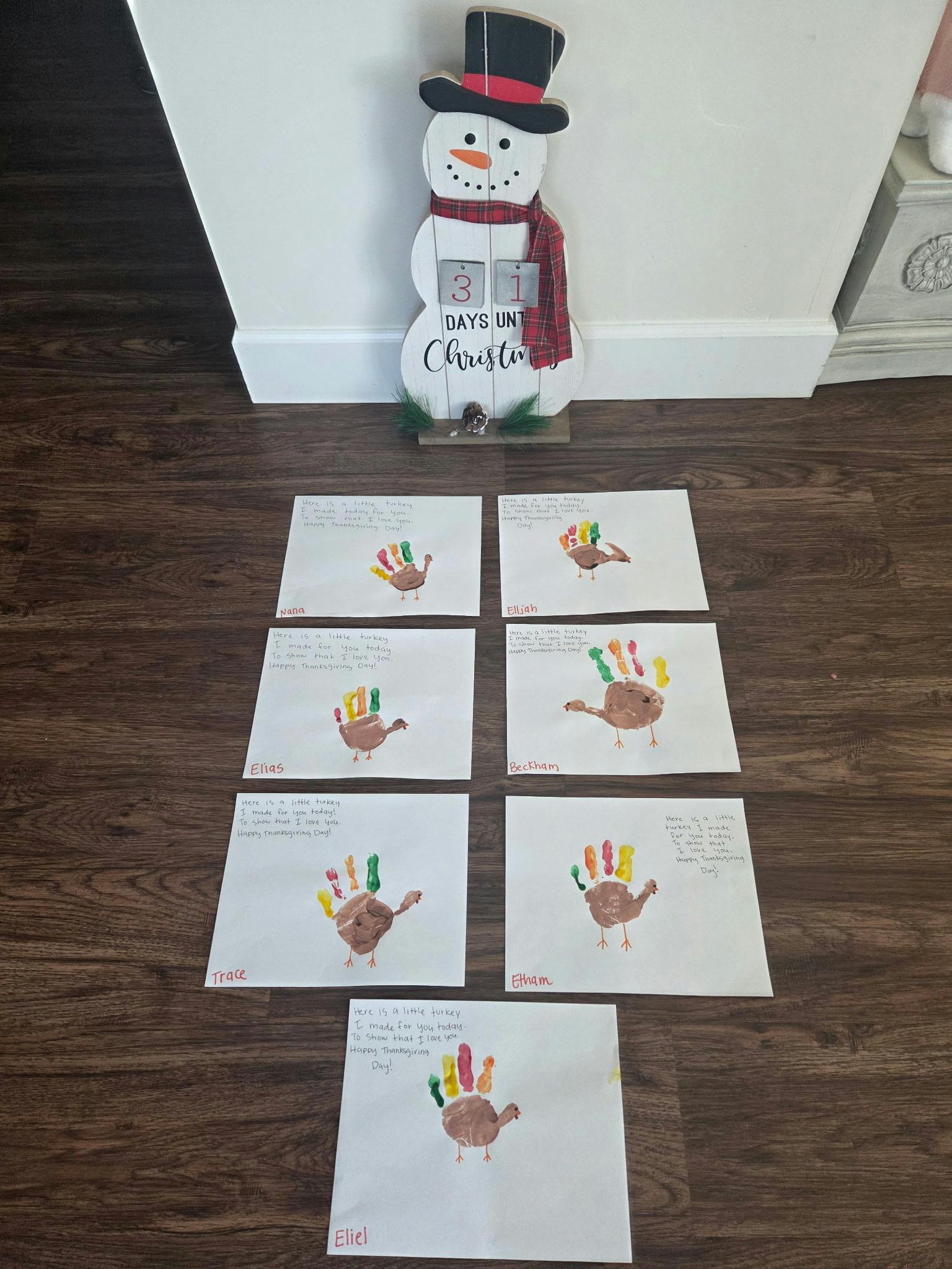 Snowman Christmas countdown next to child-made turkey handprints