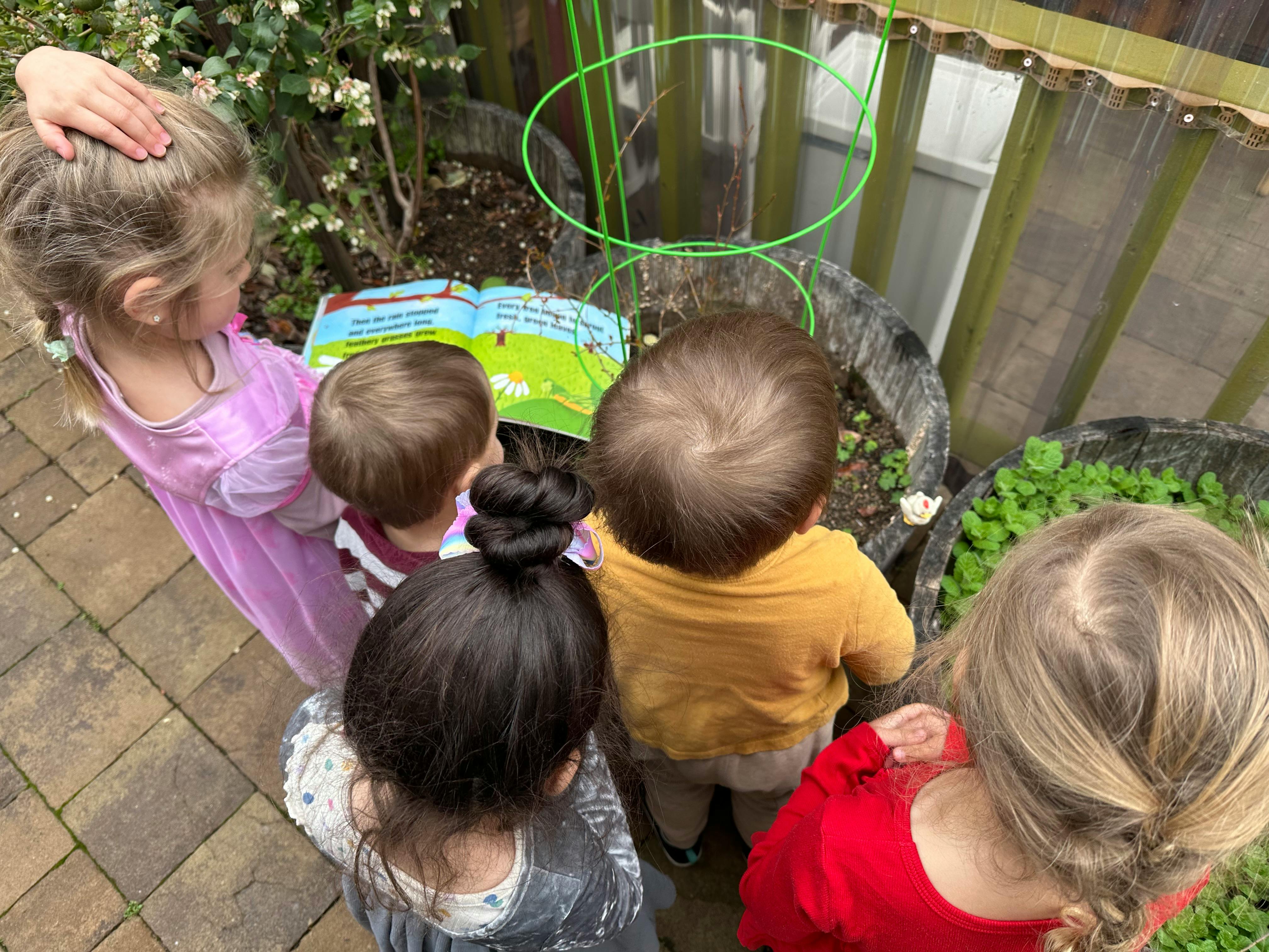 Children looking at a book and plants