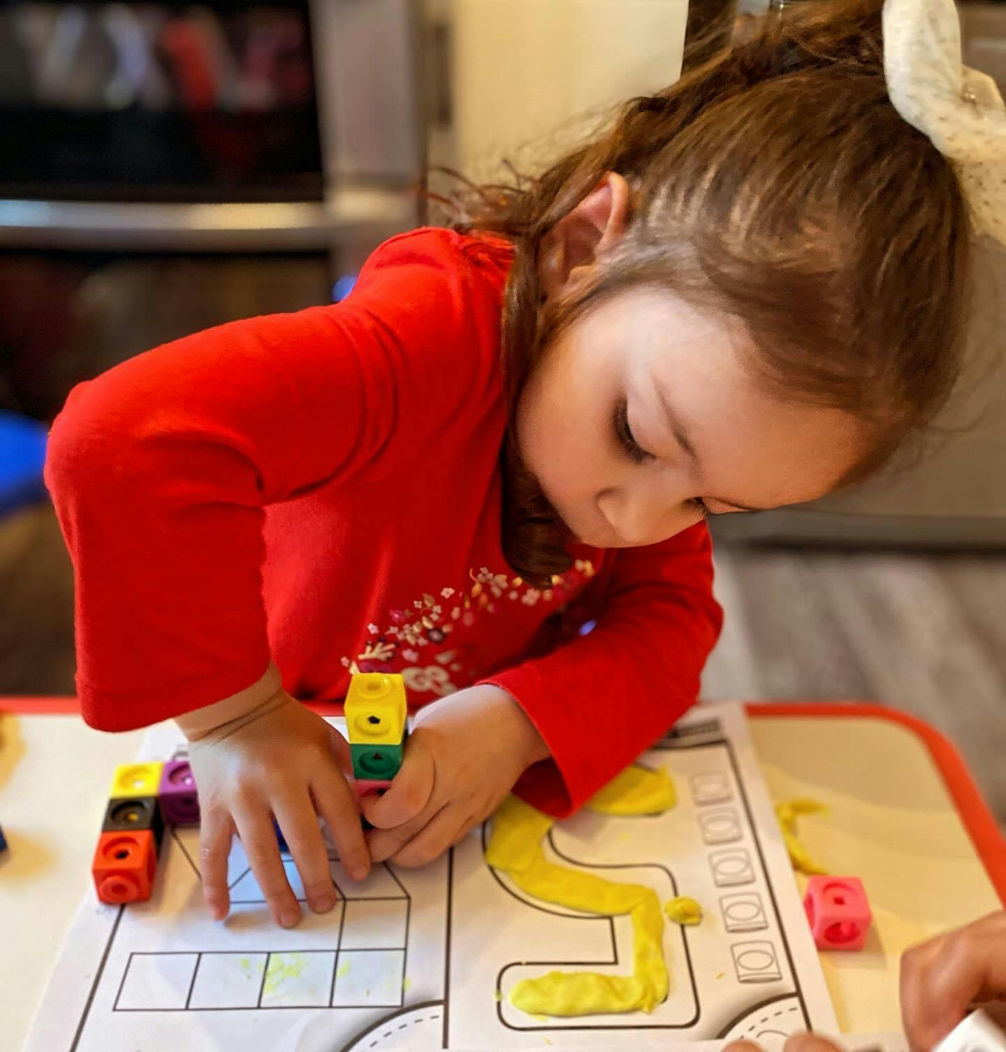Child playing with colorful blocks and a learning mat