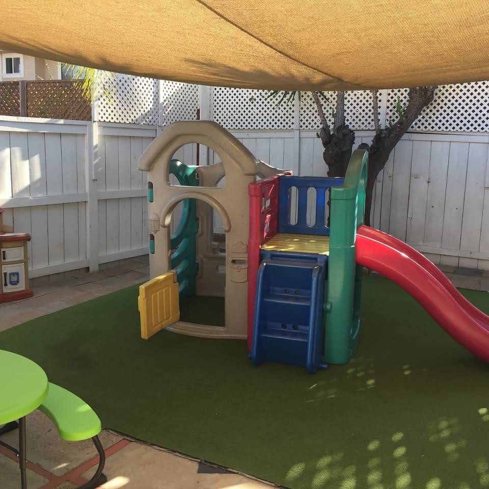 Playground with a playhouse and slide on artificial turf