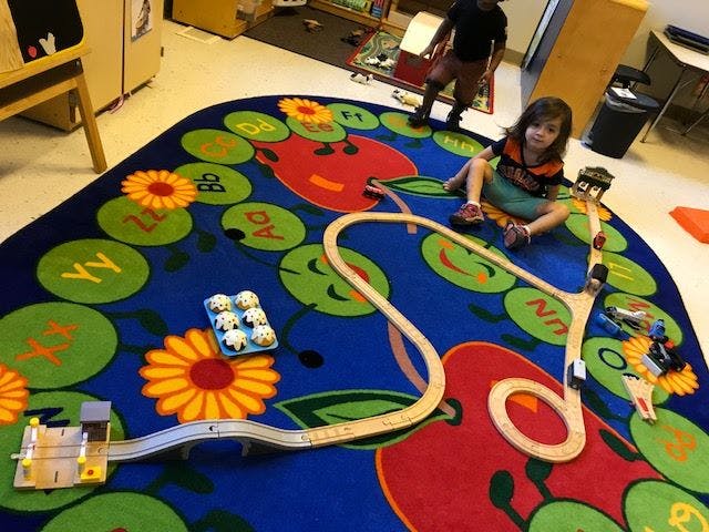 Child playing with a toy train set on a colorful rug