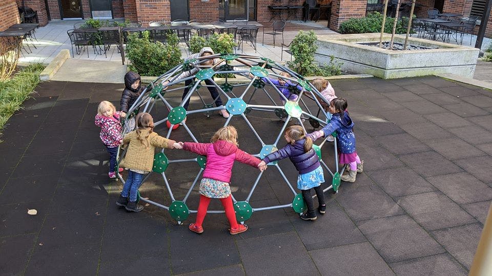 Children playing on a geodesic dome climber on a playground