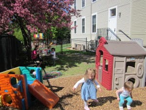 Two children playing near a playhouse and slide in a yard