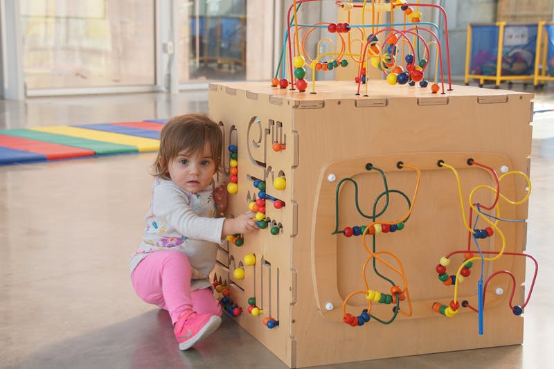 Child playing with a large wooden activity cube