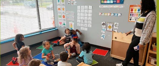 Adult standing in front of children sitting on floor in classroom