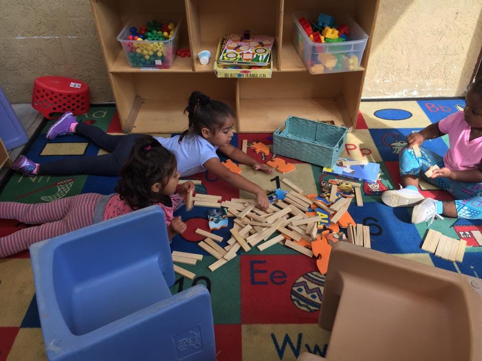 Children playing with wooden blocks on a colorful rug