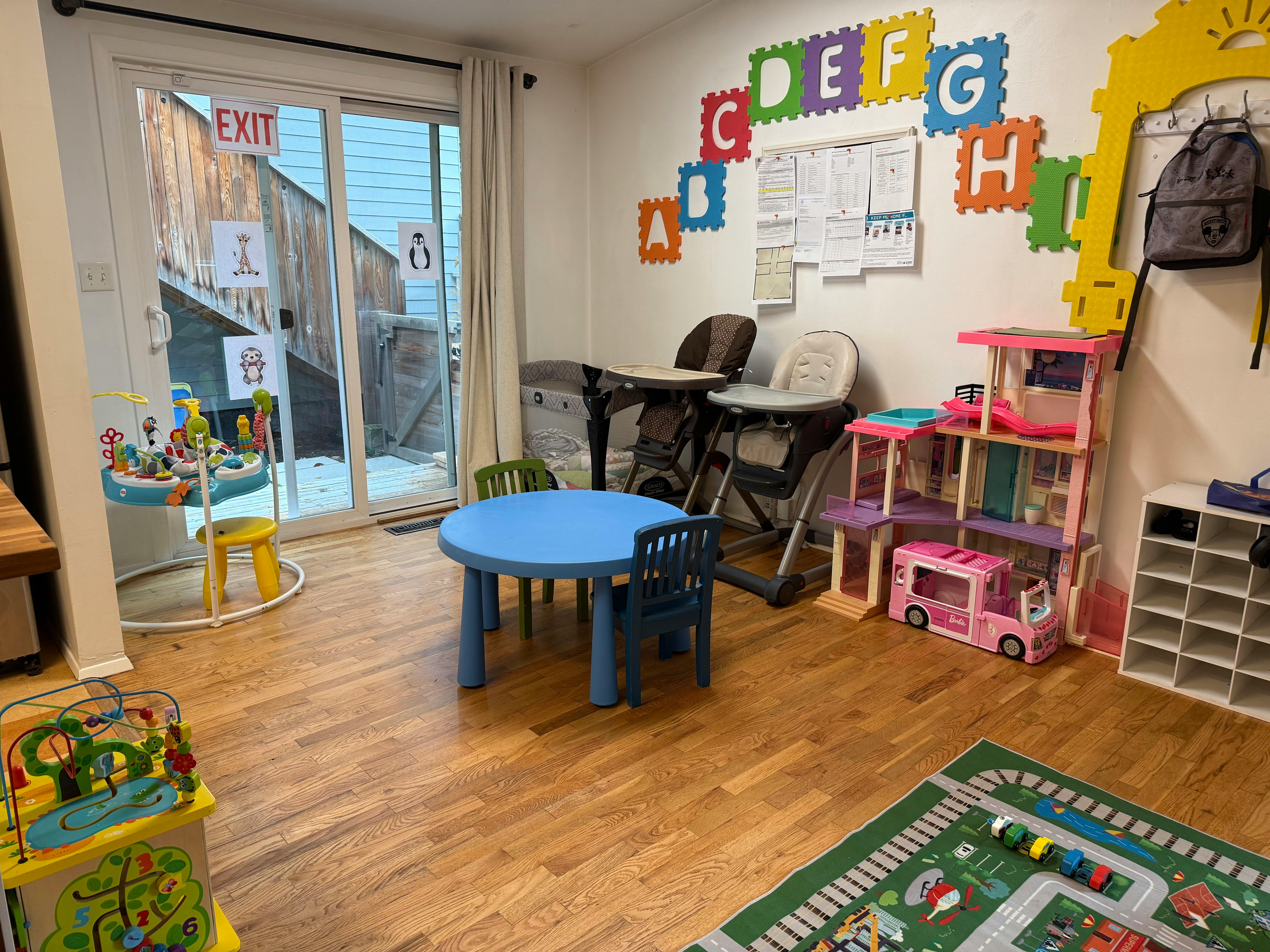 Childcare playroom with a blue table, high chairs, toys, and alphabet wall decor