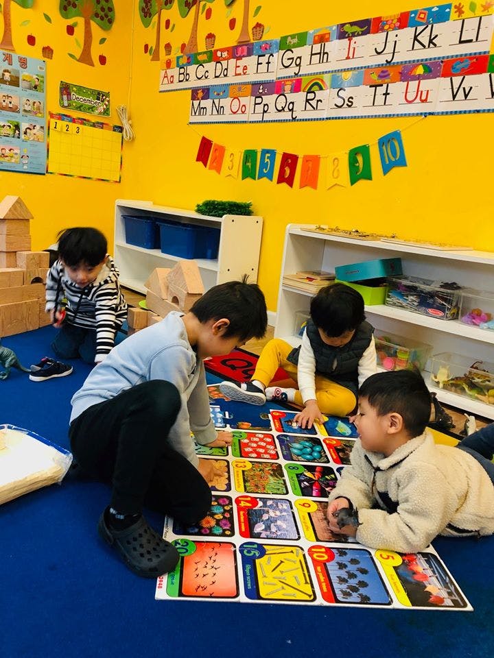 Children playing with a large board game on the floor in a classroom