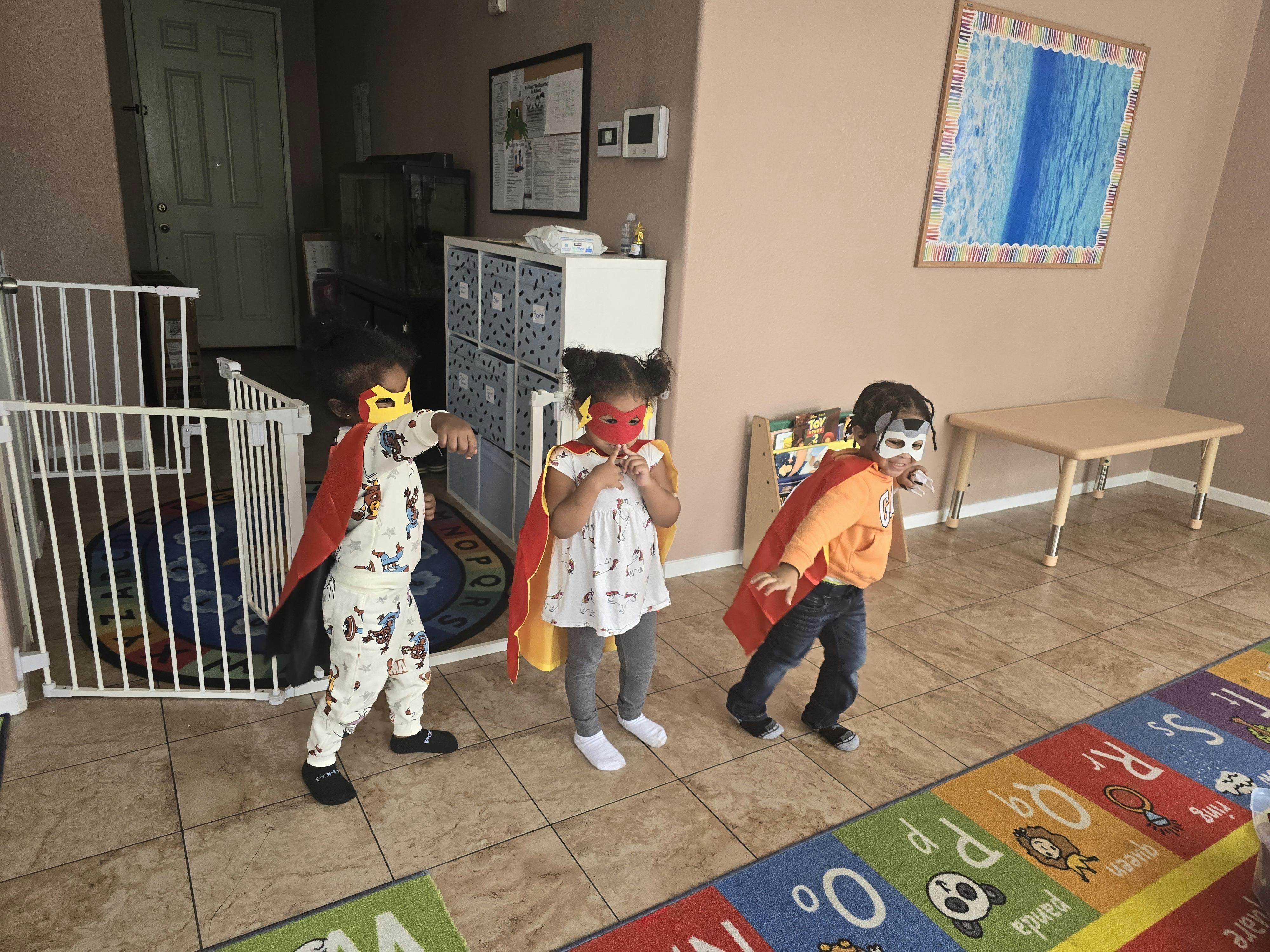 Three children in capes and masks playing indoors