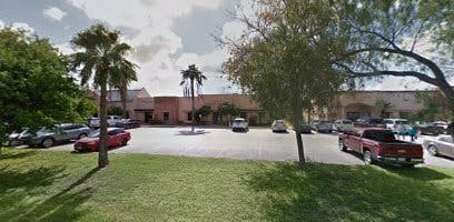 Parking lot with cars and palm trees in front of a building