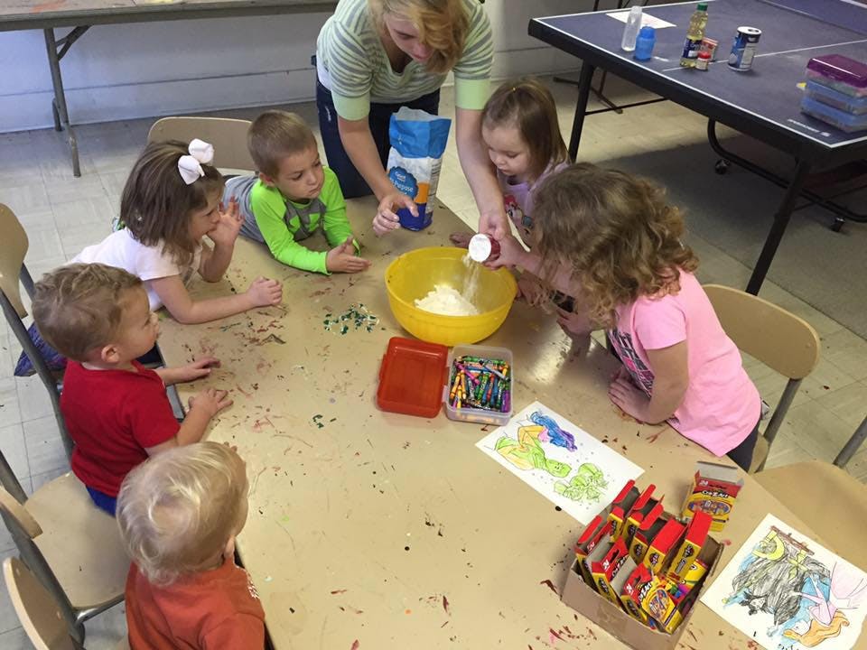 Adult and children around a table mixing ingredients in a yellow bowl