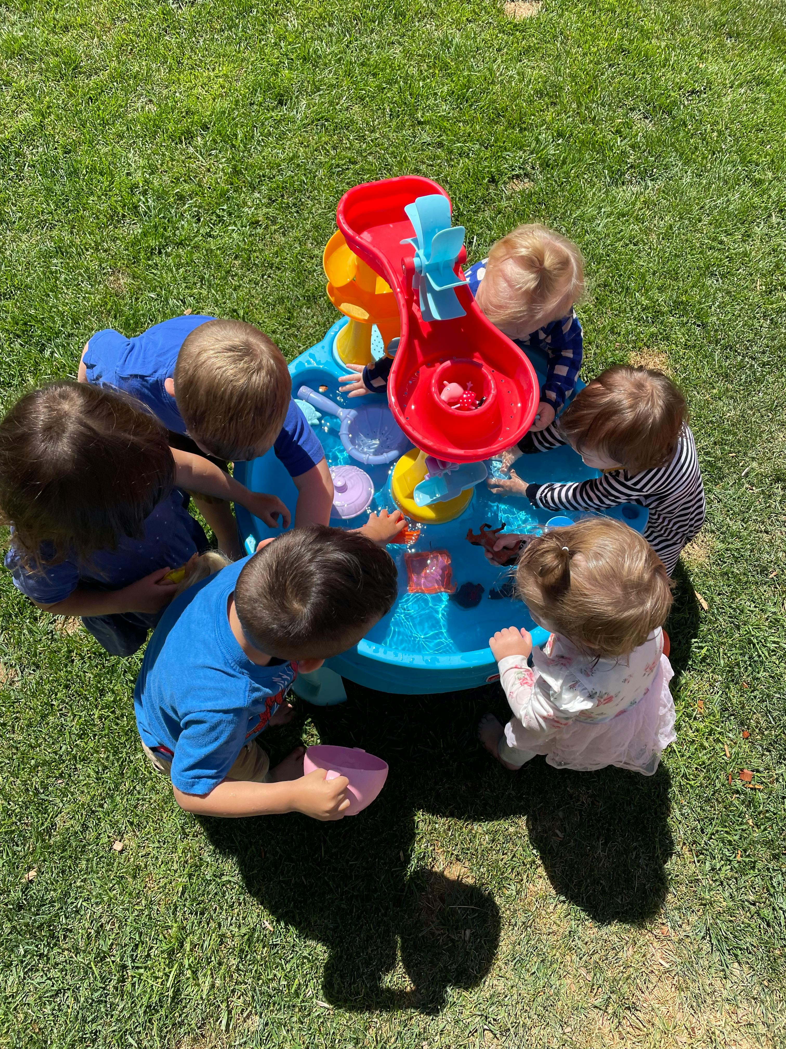 Children playing around a water table outdoors