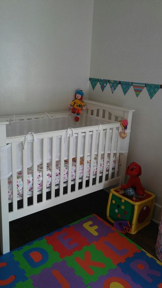 White crib with colorful alphabet playmat and toys in a room
