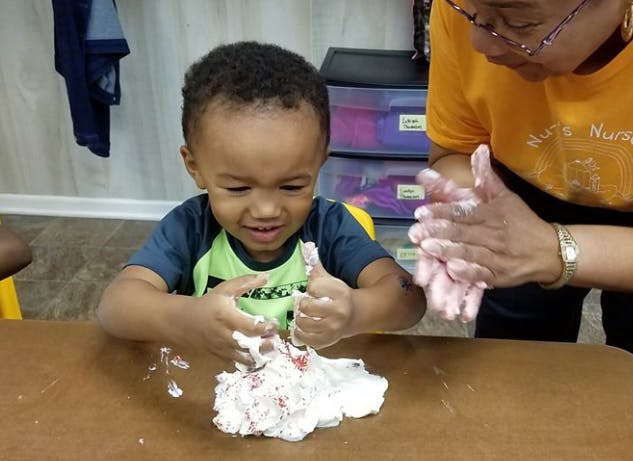 Child and person playing with white dough on a table