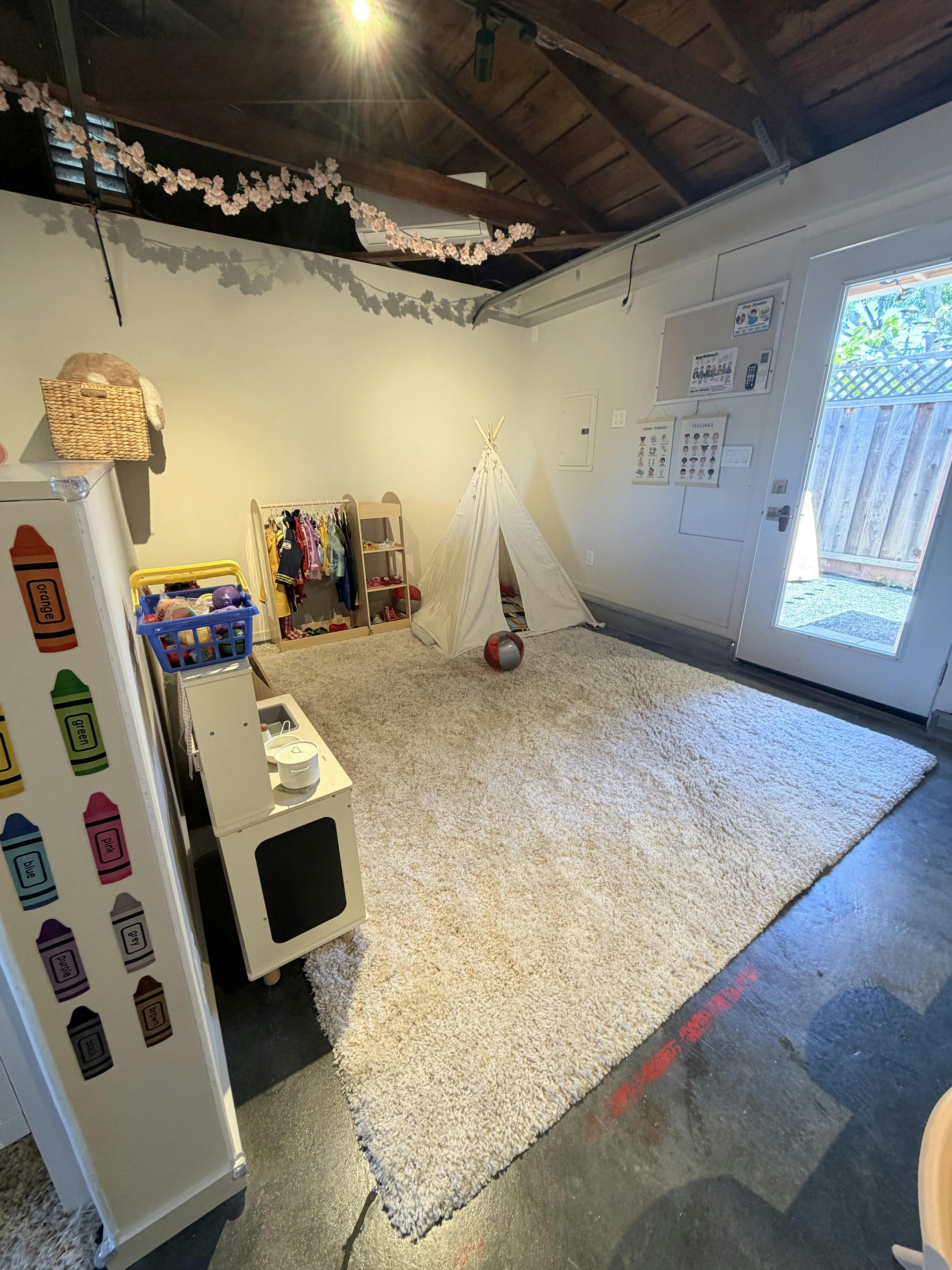 Playroom with a white tent, toy rack, and rug inside a garage
