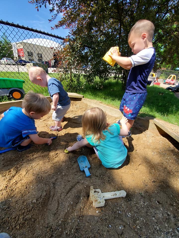 Children playing in a sandbox with toys